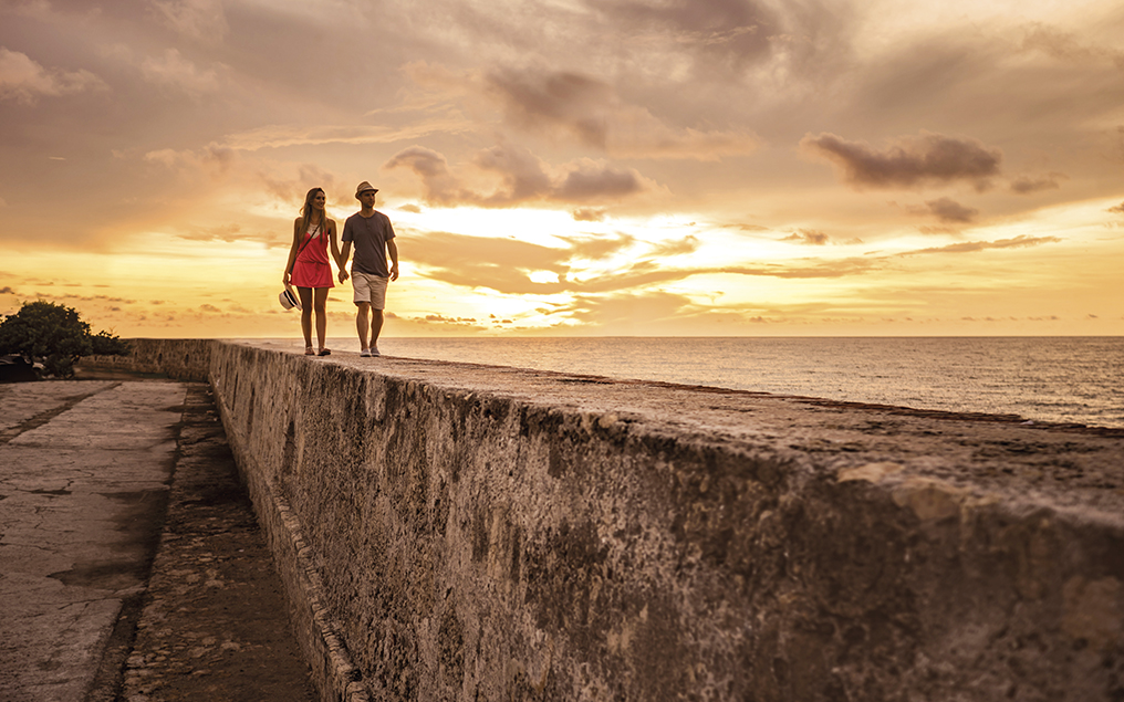 Tourists enjoying the beautiful sunset while walking on the wall at Cartagena - people traveling